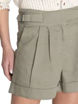 Short de tiro alto confeccionado en lino, con diseño de pinzas frontales, bolsillos laterales y detalle de hebillas ajustables en la cintura. Presenta un ruedo con dobladillo y cierre frontal.