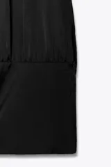 Top negro de tejido satinado con cuello halter y lazada. Cierre lateral con cremallera oculta.