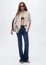 Camisa de corte recto y tejido fluido, con diseño de rayas verticales, cuello camisero, cierre frontal con botones y manga larga.