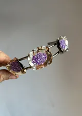 Gargantilla plateada con tres dijes de metal con forma de flor y relleno de piedras blancas.
