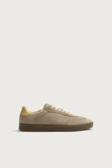 Zapatillas deportivas estilo retro de gamuza color tostado, con suela engomada marrón y detalle en tono amarillo en el talón.