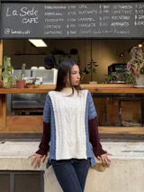 Sweater de punto con diseño de ochos y estilo patchwork, combinando paneles en colores terracota, marrón y beige. Presenta cuello redondo, mangas largas y costuras decorativas a la vista.