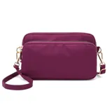 Cartera bandolera rectangular de nylon impermeable, con tres compartimentos con cierre y correa regulable.