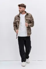 Campera tipo sobrecamisa de franela a cuadros en tonos marrones y beige, con interior forrado en corderito blanco. Presenta cierre frontal, bolsillos en el pecho con solapa y mangas largas con puños abotonados.