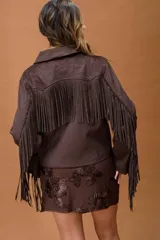 Campera de cuero marrón oscuro con diseño de flecos largos en el frente y las mangas. Presenta un corte recto, cierre frontal con cremallera y cuello clásico, con un estilo inspirado en la estética western.