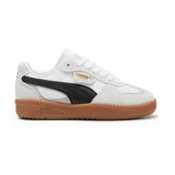 Championes urbanos Puma modelo Palermo, con diseño retro de perfil bajo. Presentan una combinación de cuero blanco y gamuza gris claro, con la icónica franja lateral en negro y suela de goma color caramelo. Incluyen el logo de la marca en dorado en el lateral y la lengüeta.