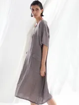 Vestido midi color visón, de lino, con cuello en V, mangas cortas y dos bolsillos frontales.