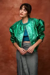 Campera de cuero con silueta oversize y corte levemente corto. Presenta cierre frontal metálico, cuello a la base y mangas amplias con detalles trenzados y recortes que aportan textura.