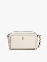 Cartera tipo bandolera Tommy Hilfiger de acabado granulado en color beige. Presenta un diseño rectangular con cierre de cremallera, bolsillo frontal exterior con cierre y el monograma TH metálico en dorado en la parte delantera. Incluye una correa extraíble.