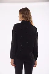 Camisa negra de poliéster con cuello clásico, cierre frontal con botones y estampado de pequeños puntos blancos.