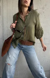Camisa verde de tejido liviano, con cuello romántico con volados, mangas abullonadas tres cuartos con puños fruncidos y cierre frontal con botones.