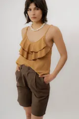 Musculosa negra con escote en V, breteles finos regulables y doble volado frontal con pespuntes.
