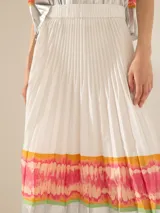 Pollera larga plisada color blanco, con cintura elastizada y estampado multicolor en los bordes del ruedo.