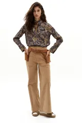 Camisa de algodón con estampado paisley en tonos azules, naranjas y amarillos. Presenta cuello camisero, mangas largas, botones de nácar en el frente y ruedo curvo, más largo en la parte trasera.