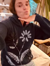 Hoodie azul marino de tejido de lana con bordado de una flor blanca en el frente.