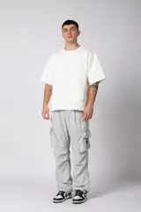 Remera de corte oversize color beige, con cuello redondo y etiqueta decorativa pequeña en el ruedo inferior.