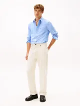 Camisa Tommy Hilfiger de corte regular en puro algodón Oxford, color celeste con sutiles rayas diplomáticas. Presenta cuello con botones, bolsillo de parche en el pecho con el logo bordado y mangas largas con puños redondeados.