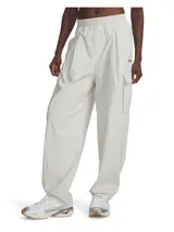 Pantalón cargo Under Armour Unstoppable para mujer, color blanco hueso, de corte holgado, con cintura elástica, bolsillos laterales y logo bordado en la pierna.