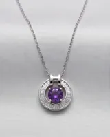 Collar de plata con cadena fina y dije circular que presenta una circonia central en color violeta rodeada por pequeñas piedras brillantes.