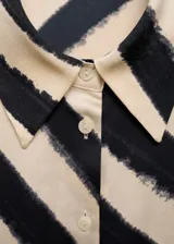 Camisa de corte recto y ajuste regular, confeccionada en tejido satinado fluido y ligero. Presenta un diseño estampado con rayas diagonales en tonos beige y negro, cuello camisero clásico, cierre frontal de botones y mangas largas con puños abotonados.