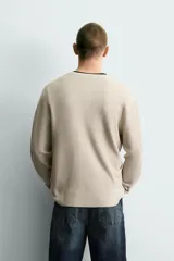 Jersey relaxed fit de punto acanalado color marrón oscuro, con cuello redondo tipo panadera y cierre frontal de tres botones. Tiene manga larga y efecto lavado.