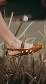 Chatita Tabi de cuero con pelo sintético estampado tipo Bambi, en tonos marrón y blanco. Presenta diseño de punta partida, tira cruzada elástica en el empeine y tira ajustable con hebilla en el talón.