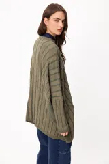 Sweater de tejido artesanal con diseño de rayas verticales en tonos camel y beige, corte holgado, cuello redondo y puños altos ajustados.