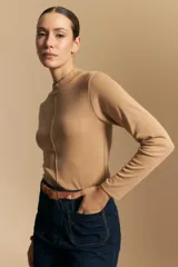 Polera de manga larga color beige, con cuello alto y costura vertical decorativa en el frente.