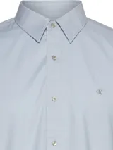 Camisa celeste de manga corta, confeccionada en tejido Oxford de algodón orgánico con elastano. Tiene cierre frontal con botones, cuello clásico y logo de Calvin Klein Jeans bordado en el pecho.