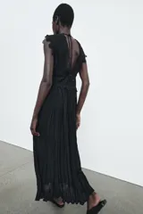 Vestido midi negro de escote pico y manga sisa, con detalles de bordados combinados a tono. Presenta un tejido plisado con efecto arrugado y cierre en la espalda con lazada y cremallera oculta.