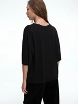 Remera de corte boxy y calce amplio, con cuello redondo y mangas cortas, de diseño minimalista y estructura relajada.