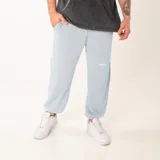 Pantalón de jogging unisex color celeste, de corte oversize, con cintura elástica y puños ajustados en los tobillos. Presenta un pequeño bordado con la palabra 'GAINS.' en la pierna izquierda.
