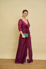 Vestido largo bordó de fiesta, con escote en V pronunciado, nudo drapeado en la cintura y tajo frontal. Las mangas son tres cuartos en tul translúcido con detalles sutiles.