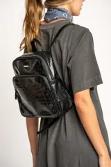 Mochila negra de cuero vegano con textura croco, tamaño mediano, con doble compartimento con cierre y correas ajustables.