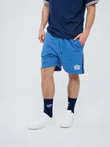 Bermuda deportiva Umbro del Club Nacional de Football, modelo Nexo para hombre, en color azul marino con detalles en rojo y blanco. Cuenta con el escudo del club bordado en la pierna derecha y el logo de Umbro en la izquierda, además de cordón ajustable en la cintura.