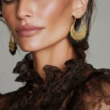 Aros tipo argolla dorados con diseño calado de filigrana y colgantes de pequeñas cuentas rojas en el borde inferior.