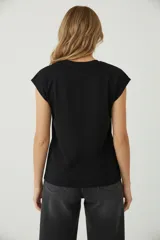 Remera blanca de algodón, de corte holgado, con cuello redondo a la base y mangas cortas con el dobladillo doblado hacia afuera.