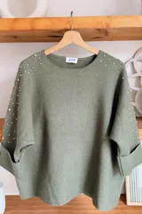 Sweater gris melange con detalles de perlas y strass aplicados en las mangas, de corte holgado y mangas largas.