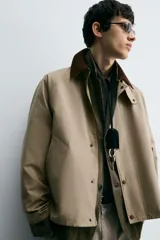 Cazadora de corte relajado confeccionada en tejido técnico con algodón. Presenta cuello de solapa en pana a contraste, cierre frontal con cremallera oculta por solapa con botones a presión, bolsillos de vivo en la cadera y manga larga.