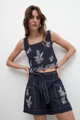 Short azul marino con bordado floral blanco, tiro alto y cinturón de lazo.