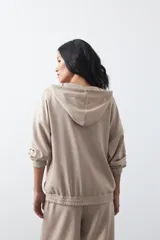 Campera con capucha y cierre frontal, de silueta relajada, hombros caídos y bolsillos laterales. Presenta terminaciones elastizadas en puños y ruedo, con líneas de recorte frontales y cierre metálico con tirador circular.