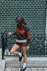 Sweater de punto con diseño de rayas horizontales anchas en color negro y marrón. Presenta cuello polo, cierre frontal con botones y mangas largas con puños ajustados.