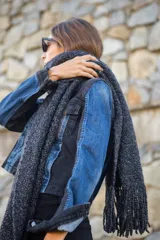 Chal largo tejido de punto grueso color gris oscuro con flecos en los extremos.