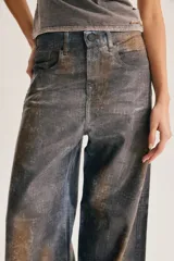 Jean de corte amplio en toda la pierna, con textura desgastada y efecto animal print de serpiente o cocodrilo en tonos gris y terracota.