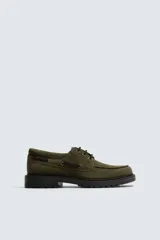 Zapato tipo náutico de hombre, confeccionado en piel con acabado de serraje en color verde oliva. Presenta cordonera con tres pasados, horma redonda y suela track dentada en color negro.