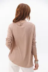 Buzo color beige de tejido suave, con escote en V y mangas largas.