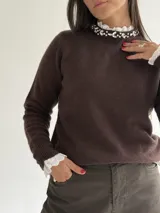 Sweater de punto color marrón chocolate, con cuello redondo decorado con apliques de pedrería y detalle de puntilla blanca en el cuello y los puños.