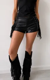 Micro short de cuero sintético negro con cordones laterales ajustables y flecos decorativos en los costados.