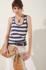 Musculosa de algodón con cuello redondo y escote en U, con diseño de rayas horizontales azules y blancas. Presenta un detalle de costura en forma de 'X' en el escote.