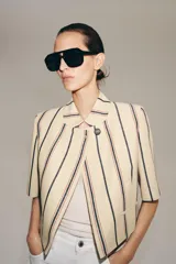 Blazer cropped ZW Collection confeccionada en mezcla de algodón, con diseño a rayas verticales en tonos azul y rojo sobre base beige. Presenta cuello redondo, manga corta, forro interior a tono y cierre frontal con un botón.